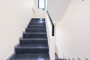 Eine Treppe mit schwarzen Stufen und weißen Wänden, die zu einem Ausgangsschild führt.