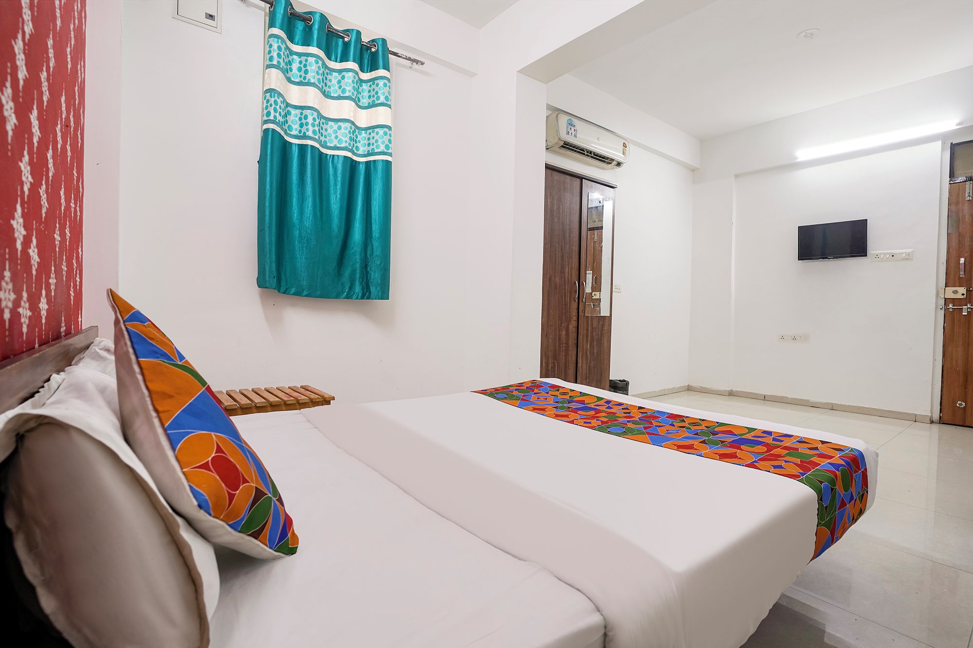 Una habitación de hotel con una cama, un televisor montado en la pared y un equipo de aire acondicionado.