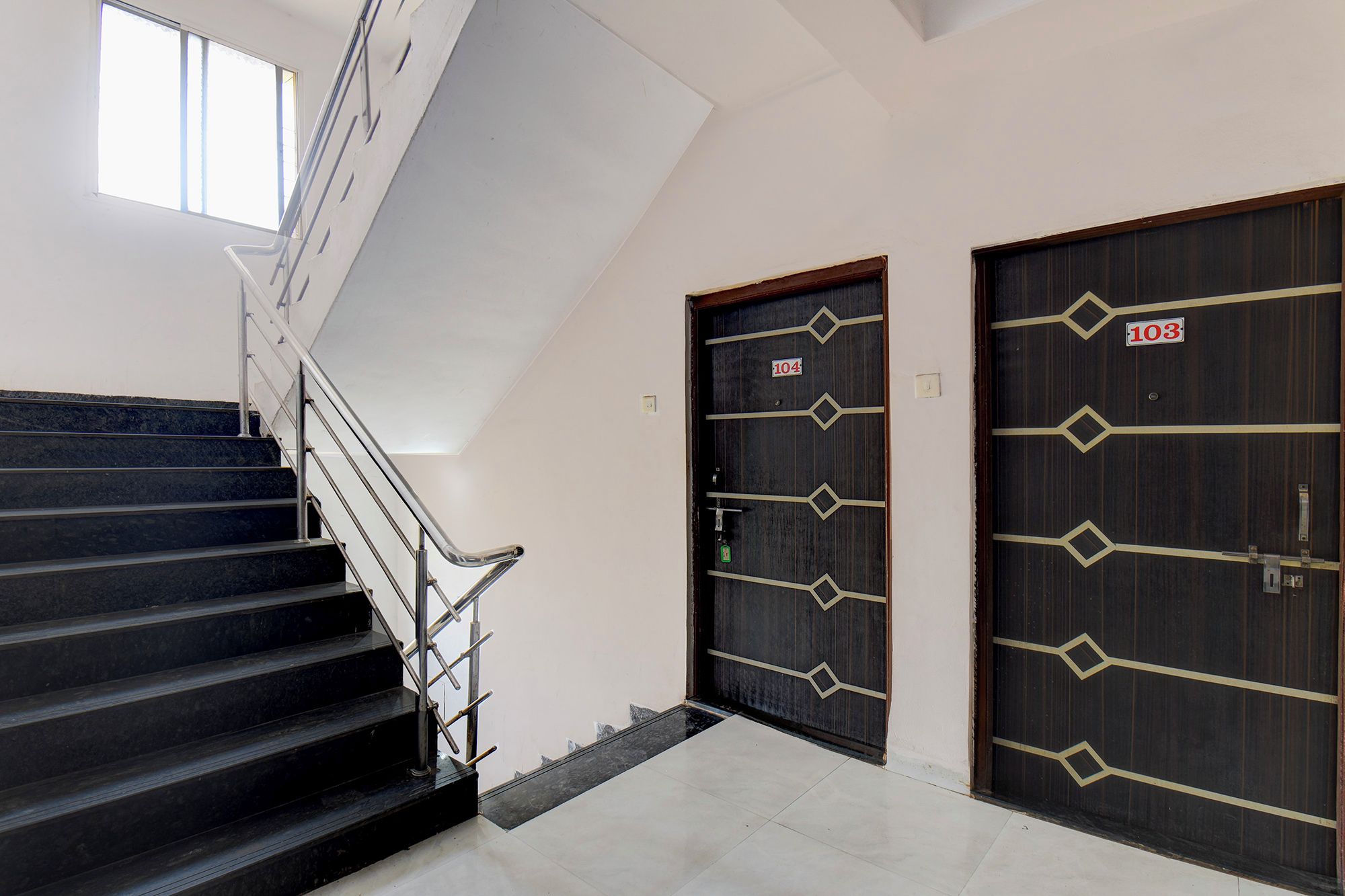 A staircase leading to a landing with two dark wooden doors, each marked with a number.