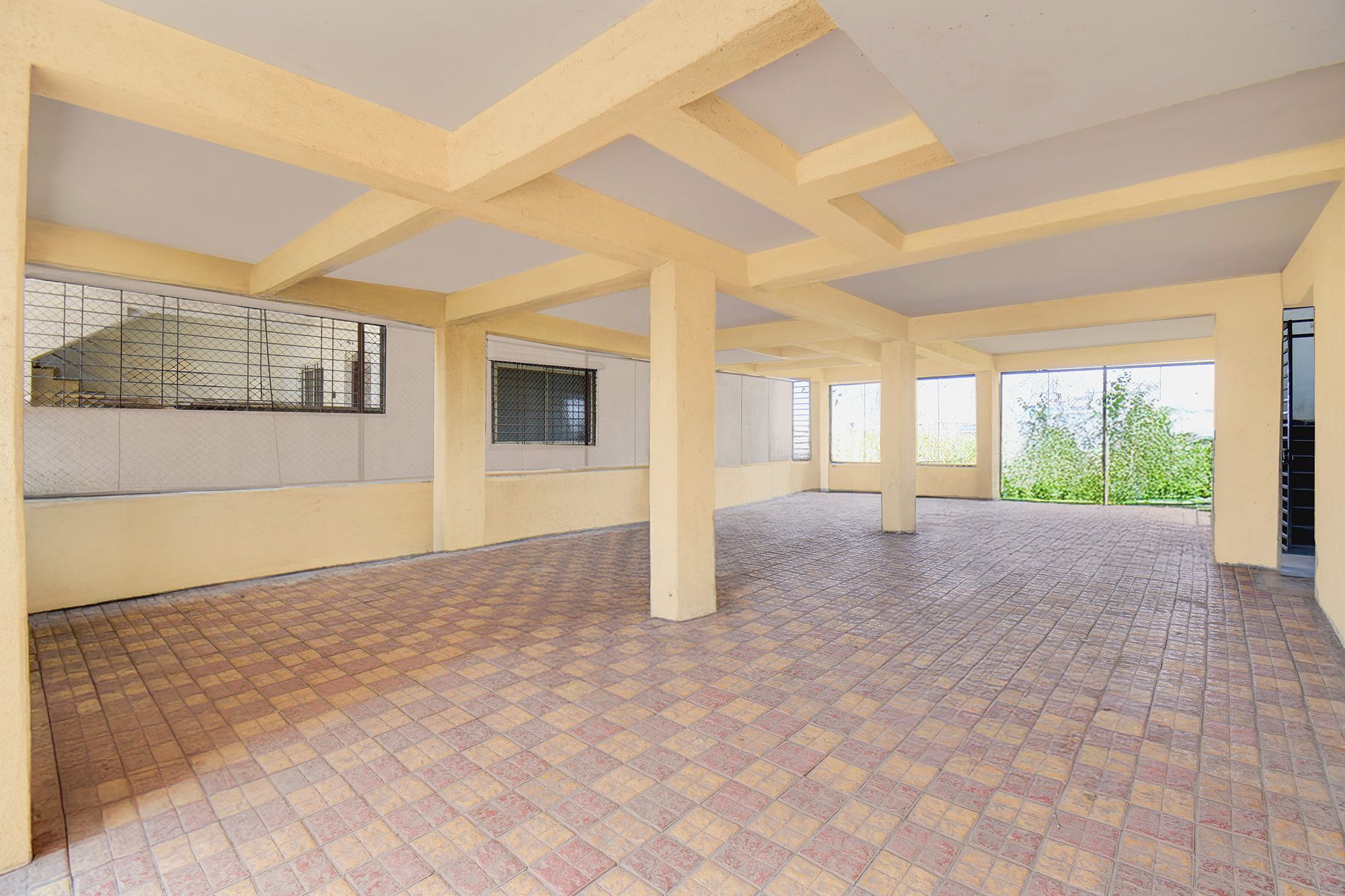 Una habitación amplia con suelo de baldosas, ventanas grandes y un techo alto con vigas a la vista.