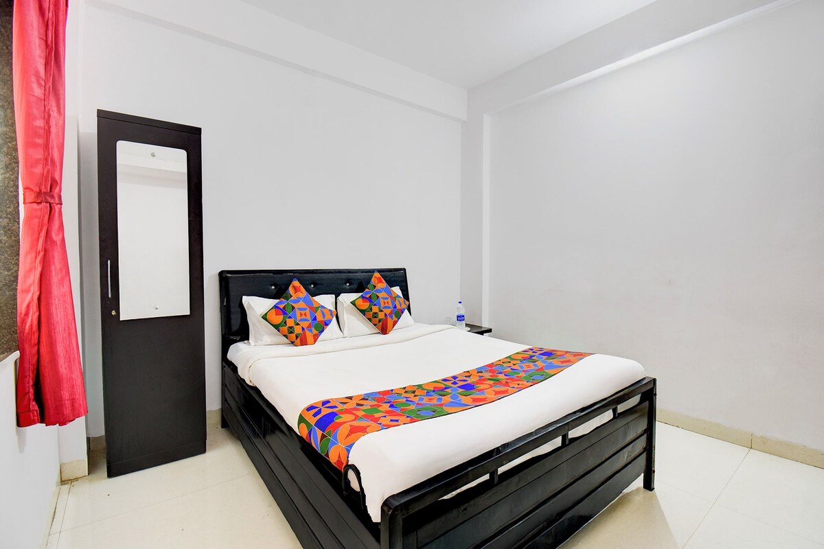 A neatly made bed with a colorful geometric-patterned bedspread and pillows, a black headboard, and a white wall.