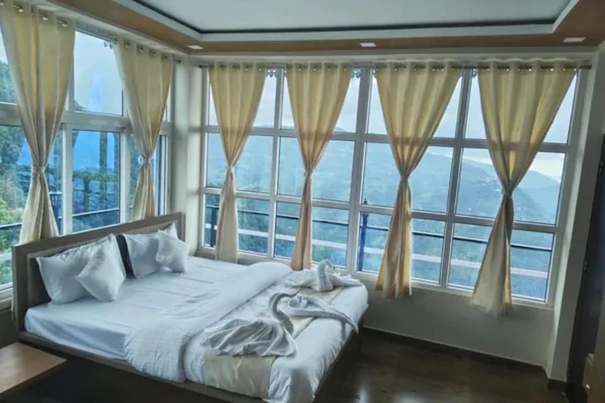 A bedroom with a bed, curtains, and a view of the outdoors.