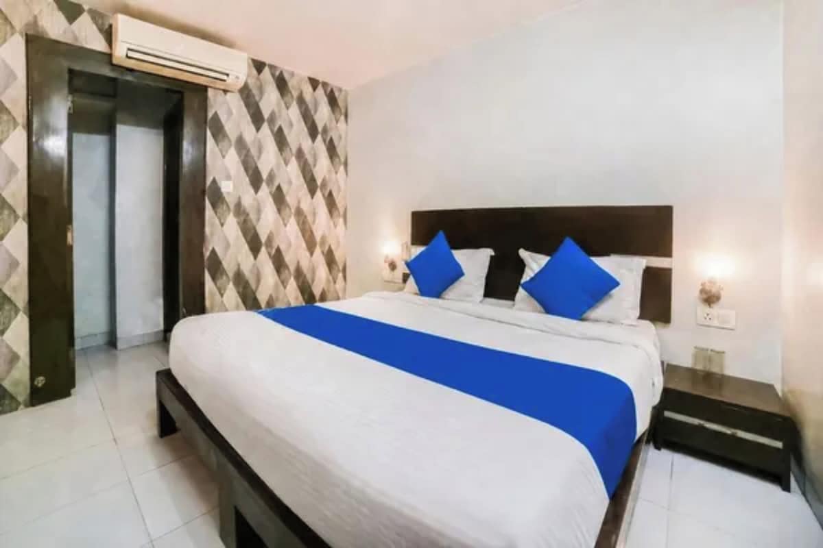 Habitación de hotel con una cama grande, cabecera, dos lámparas de noche y una pared con diseño.