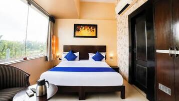 Habitación de hotel con cama, una mesa con hervidor, un cuadro en la pared y vistas a través de la ventana.