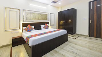 Ein Hotelzimmer mit einem großen Bett, einem Kleiderschrank und einem Spiegel mit geometrischen Mustern.