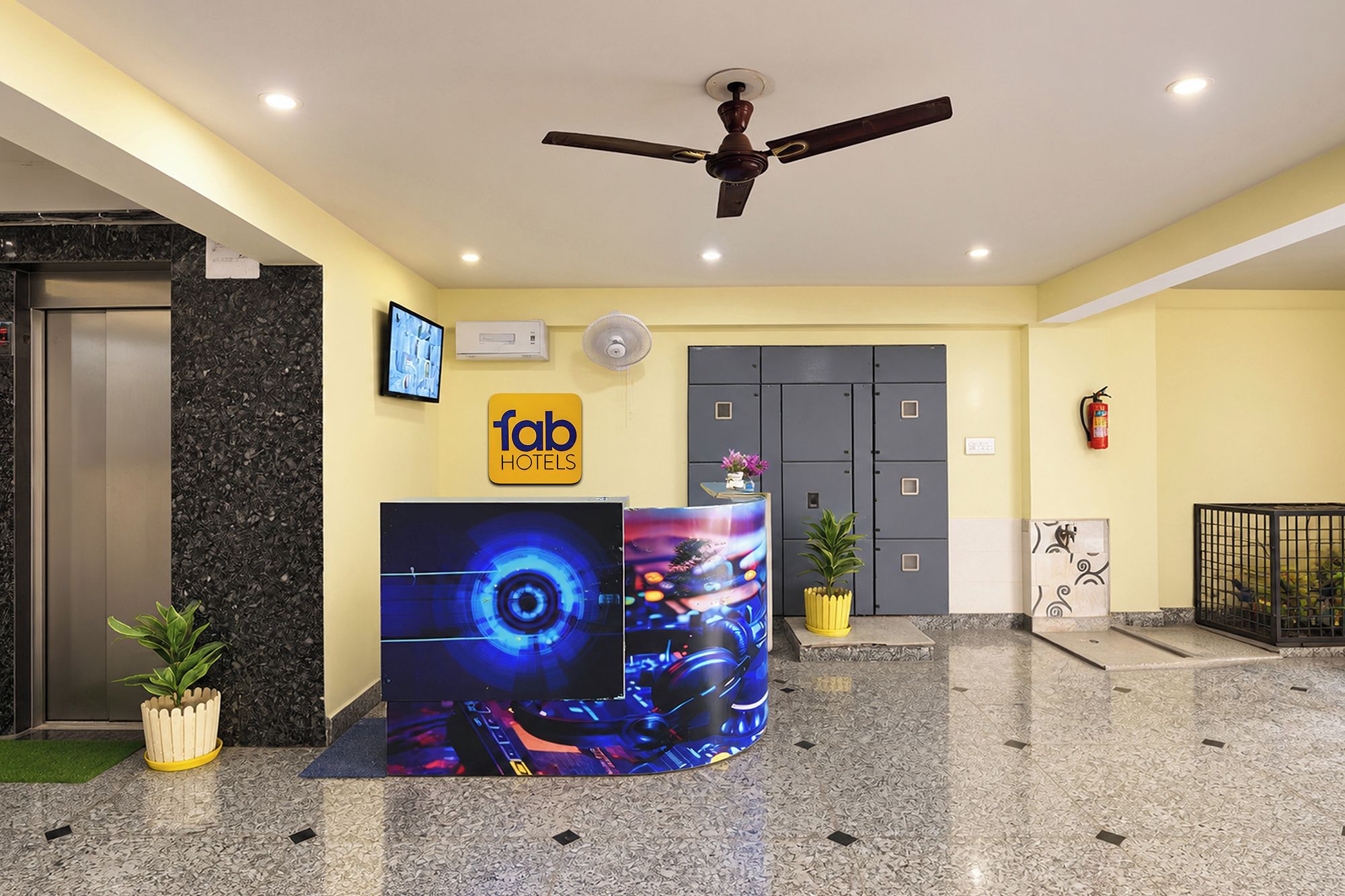 Ein Hotel-Empfangsbereich mit modernem Design, inklusive eines digitalen Displays, einem Deckenventilator und einer Rezeption.