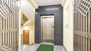 Ein Korridor mit einem Metallgitter, einer Treppe und einem Aufzug.