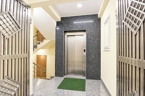 Um corredor com portão de metal, escada e elevador.