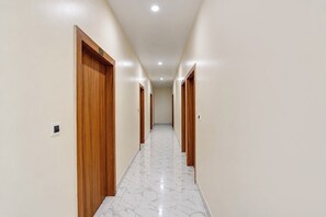 Un pasillo con puertas de madera, suelo de mármol e iluminación empotrada en el techo.