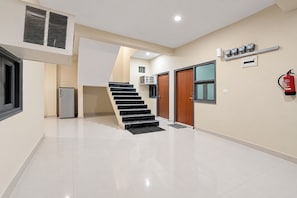 Un interior moderno con una escalera, un extintor y un refrigerador pequeño.