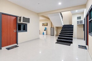 A modern interior with a wooden door, a staircase, and a water dispenser. - FabHotel Skyline Sector 101 (Noida)