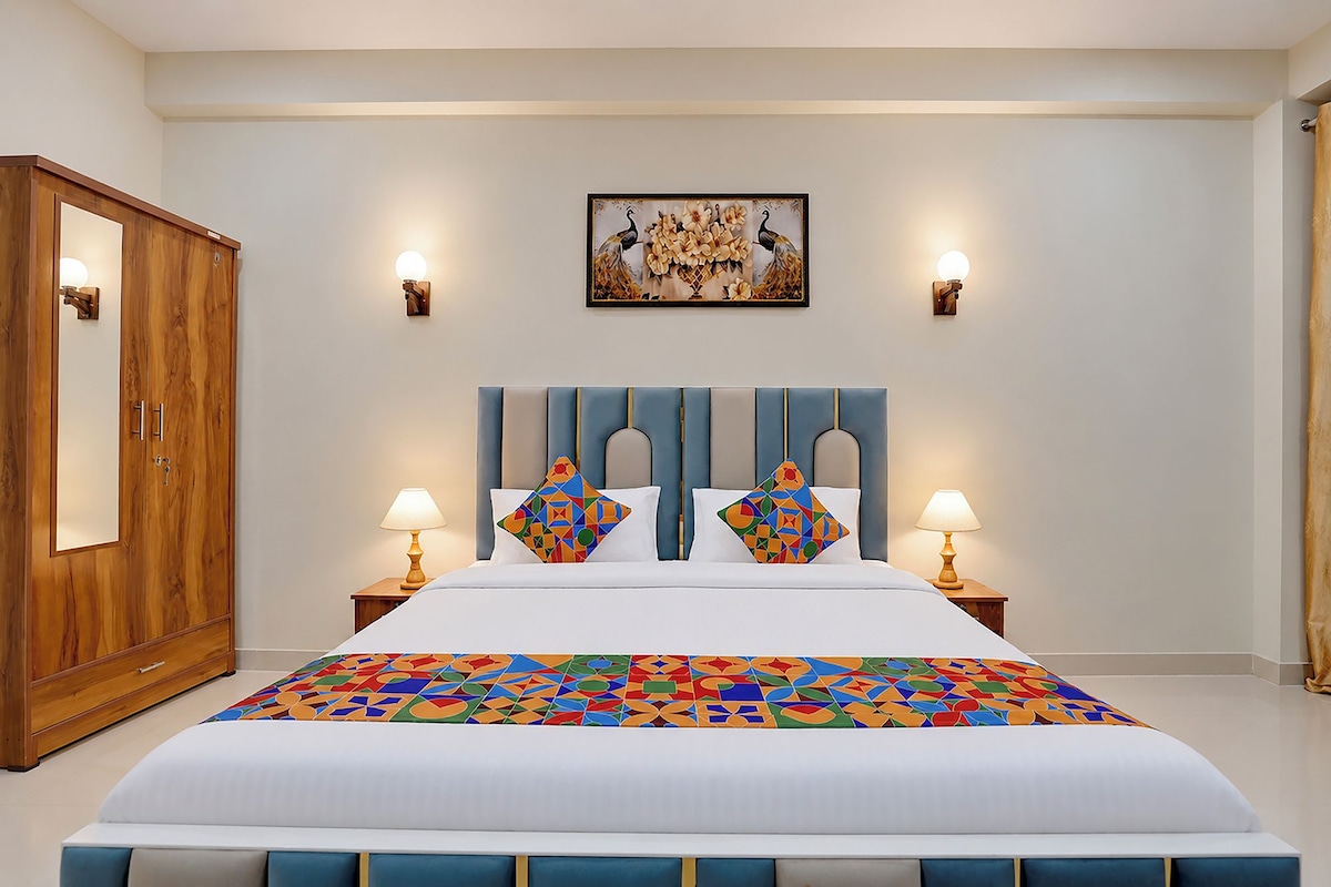 Habitación de hotel con una cama grande, dos lámparas de noche, un armario de madera y un cuadro colgado en la pared.