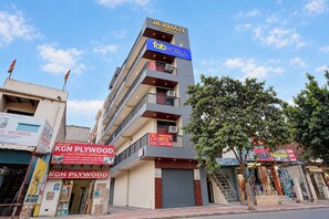 Un edificio de varios pisos con un letrero llamativo para JK Bhati Complex y FabHotels.