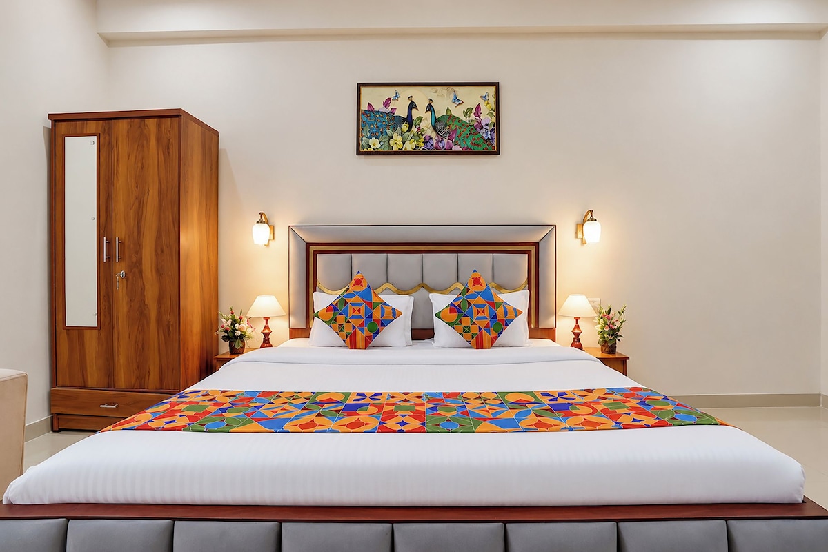Una habitación de hotel con una cama grande, un armario de madera, dos lámparas de noche y un cuadro colgado en la pared.
