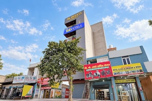 Un edificio comercial con varias fachadas, que incluye un hotel llamado 'Jk Bhati Complex' y un letrero para 'Royal Glass Aluminium & Work'.