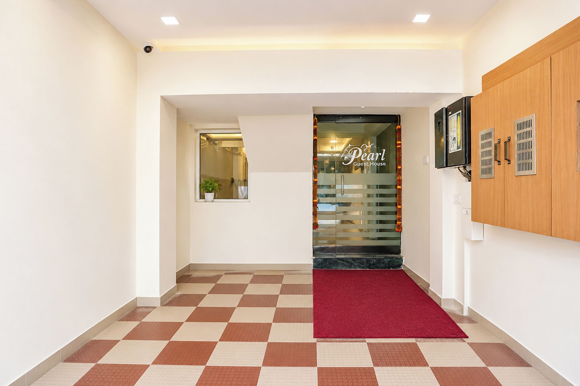A hotel lobby with a checkered floor, a red carpet, and a reception desk.