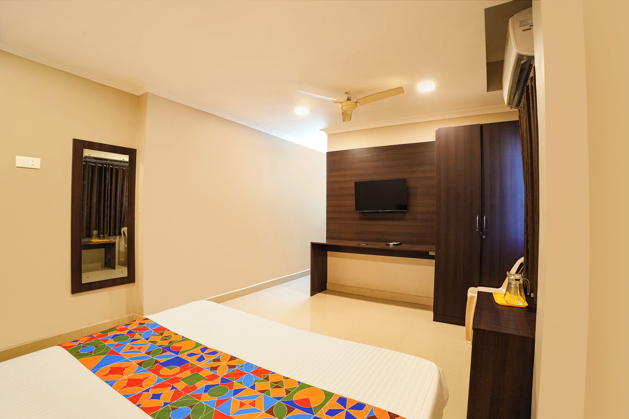 A hotel room with a bed, a television, a desk, and a wardrobe.