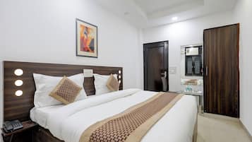 A hotel room with a bed, bedside table, lamp, and a painting on the wall.