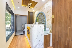 A reception desk with a marble top, a wooden floor, and a view of a staircase leading to another area. - FabHotel Fortune Tulsi Nagar (Indore)
