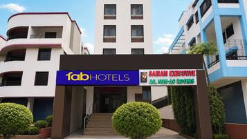 Entrada de hotel com placa indicando 'fabHOTELS' e 'QUARTOS EXECUTIVOS SAIRAM, SEM AR CONDICIONADO'.