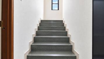 Una escalera con barandilla que lleva a un rellano con un ventanal pequeño.