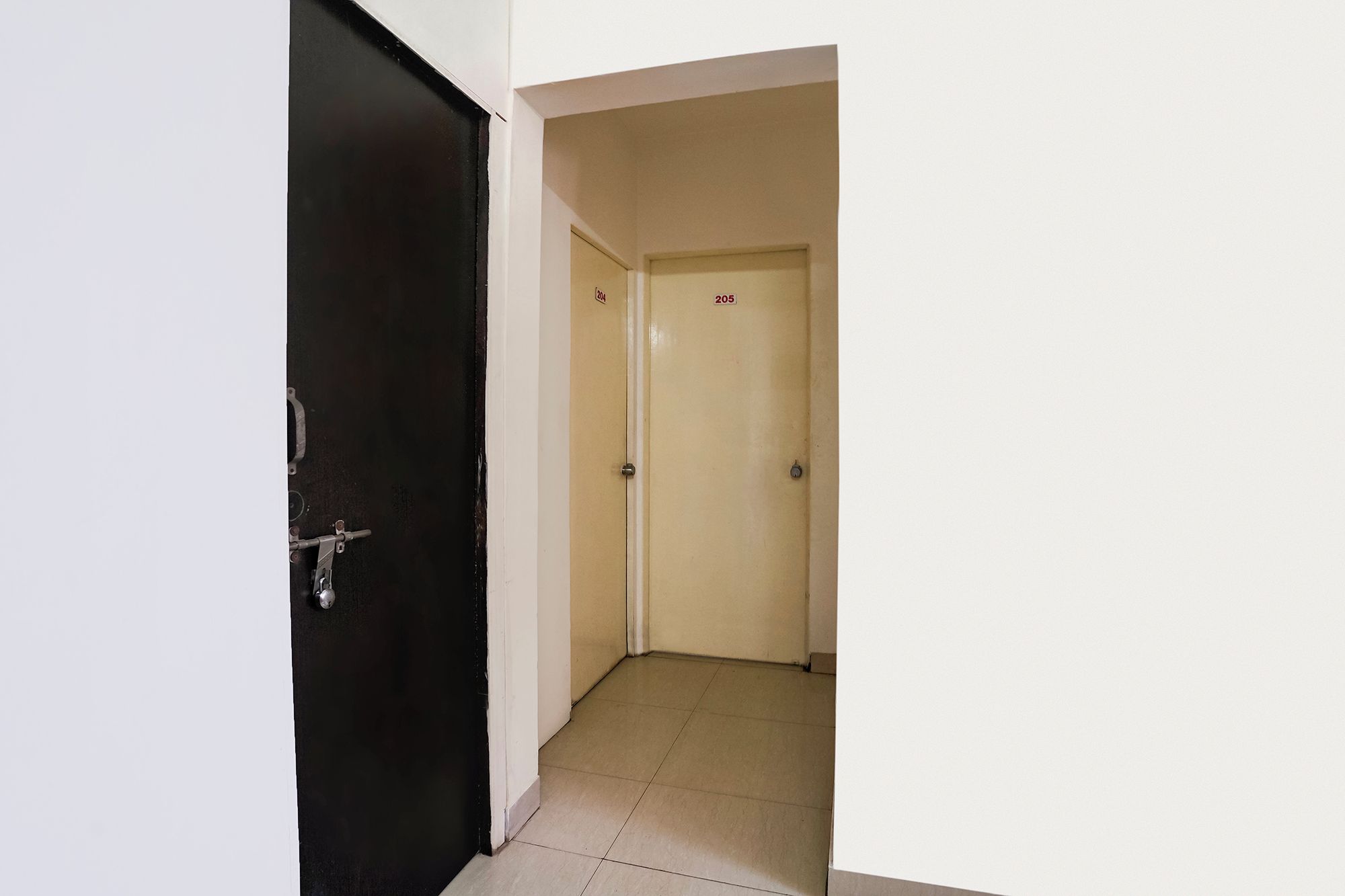 Un pasillo con una puerta negra a la izquierda y una puerta color beige a la derecha.