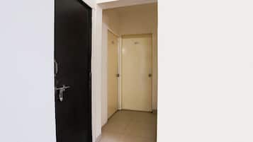 Un pasillo con una puerta negra a la izquierda y una puerta color beige a la derecha.