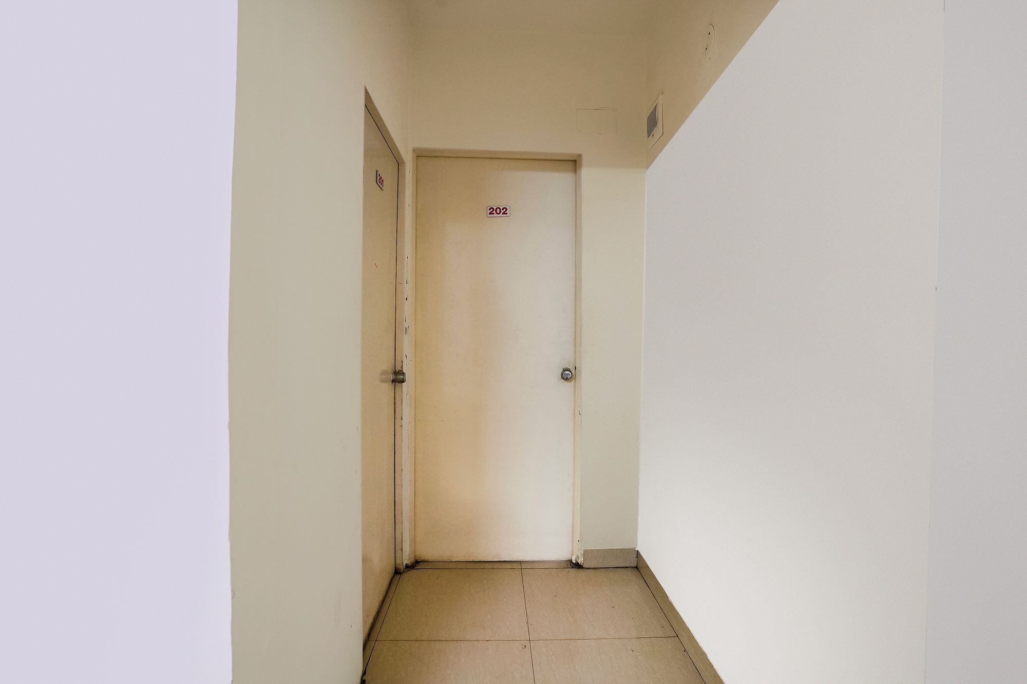 A narrow hallway with a door labeled '202' and a visible door handle.