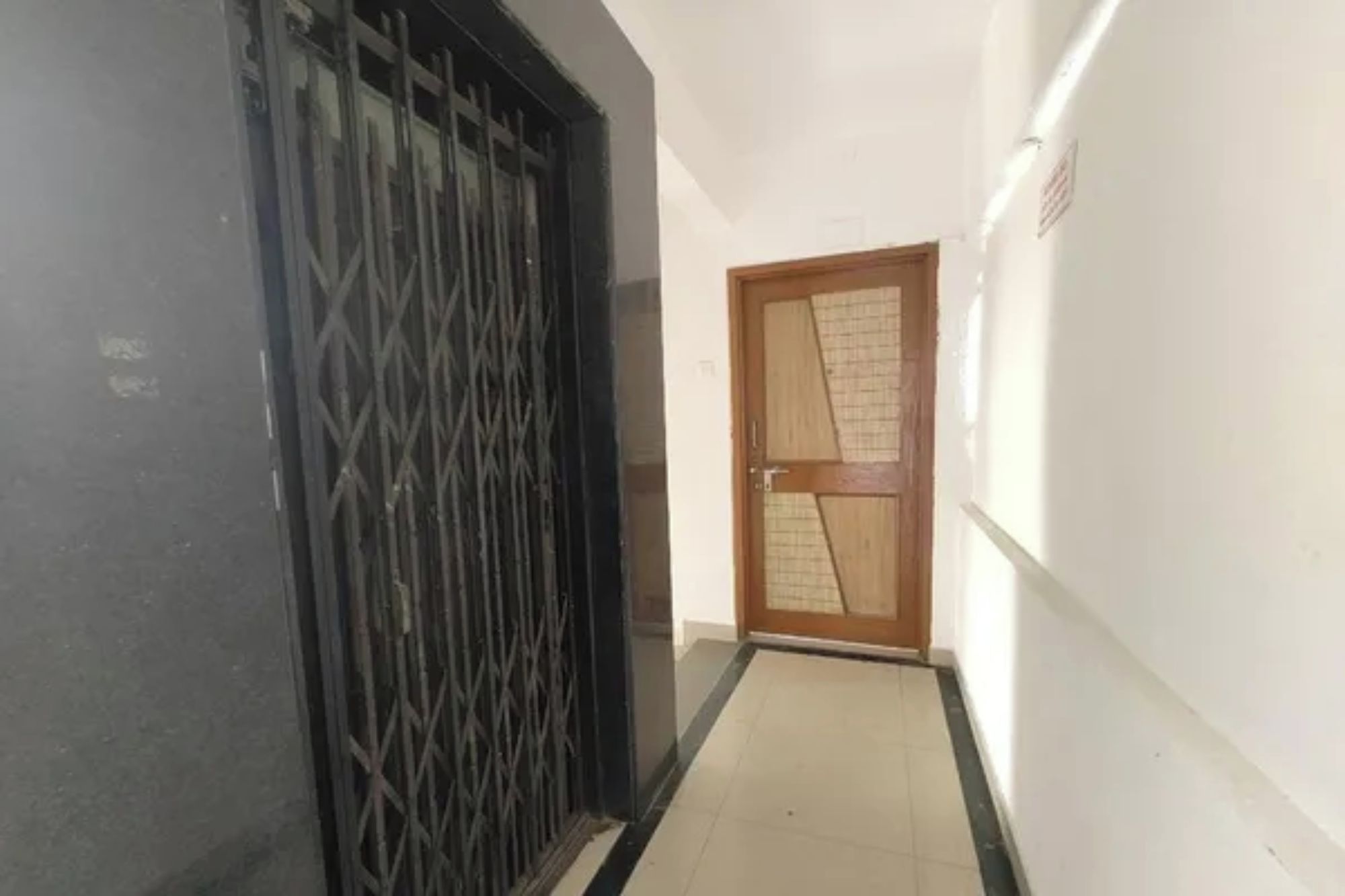 A corridor with a metal gate and a wooden door with a geometric pattern.