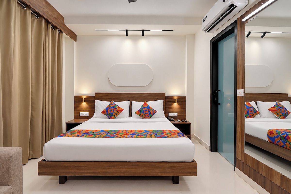 Una habitación de hotel moderna con una cama grande, mesitas de noche, un espejo y un equipo de aire acondicionado.