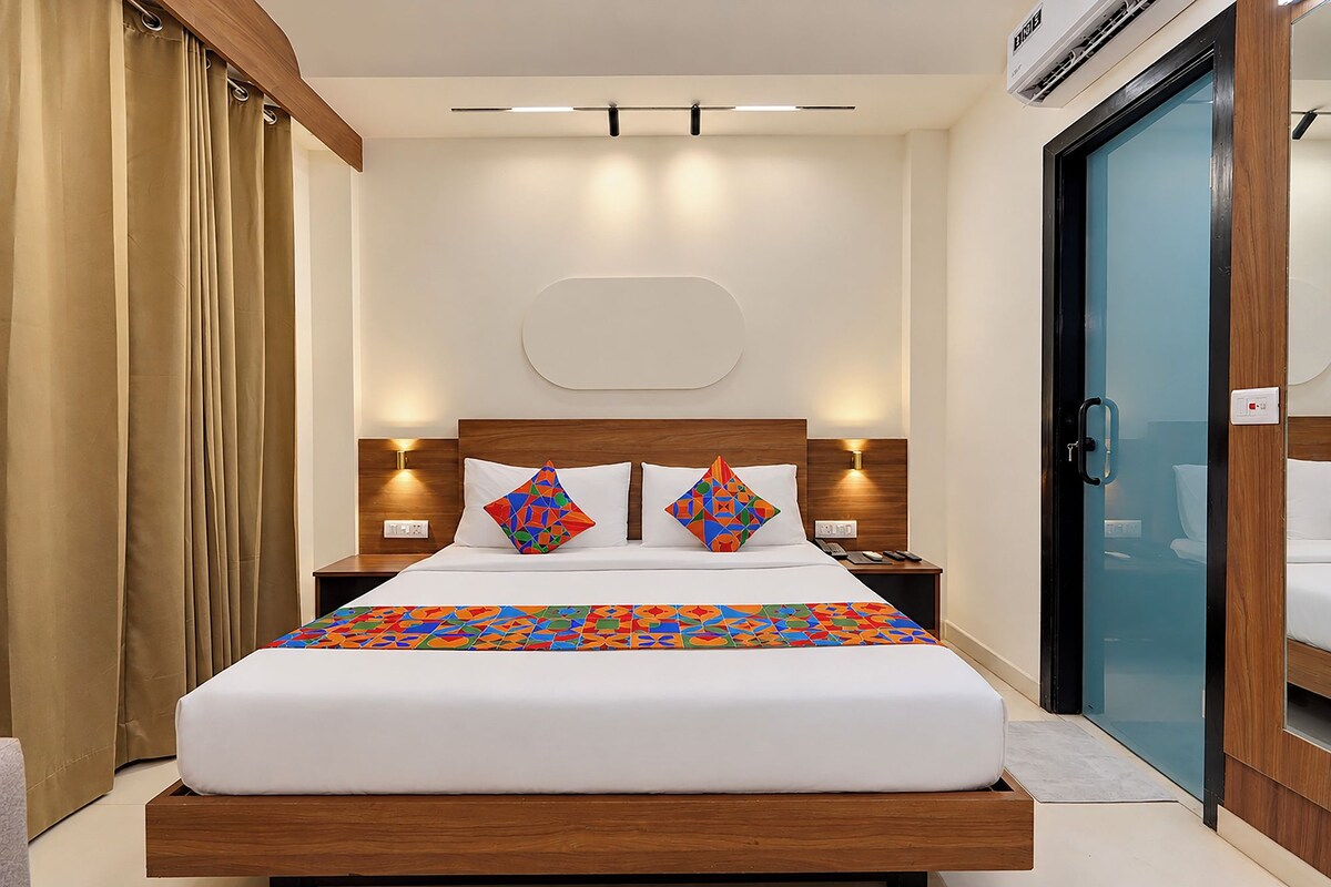 Habitación de hotel con cama, mesitas de noche, lámpara de pared y puerta con manija.