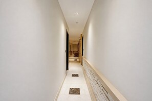 Un pasillo estrecho con suelo de baldosas y un radiador fijado a la pared.