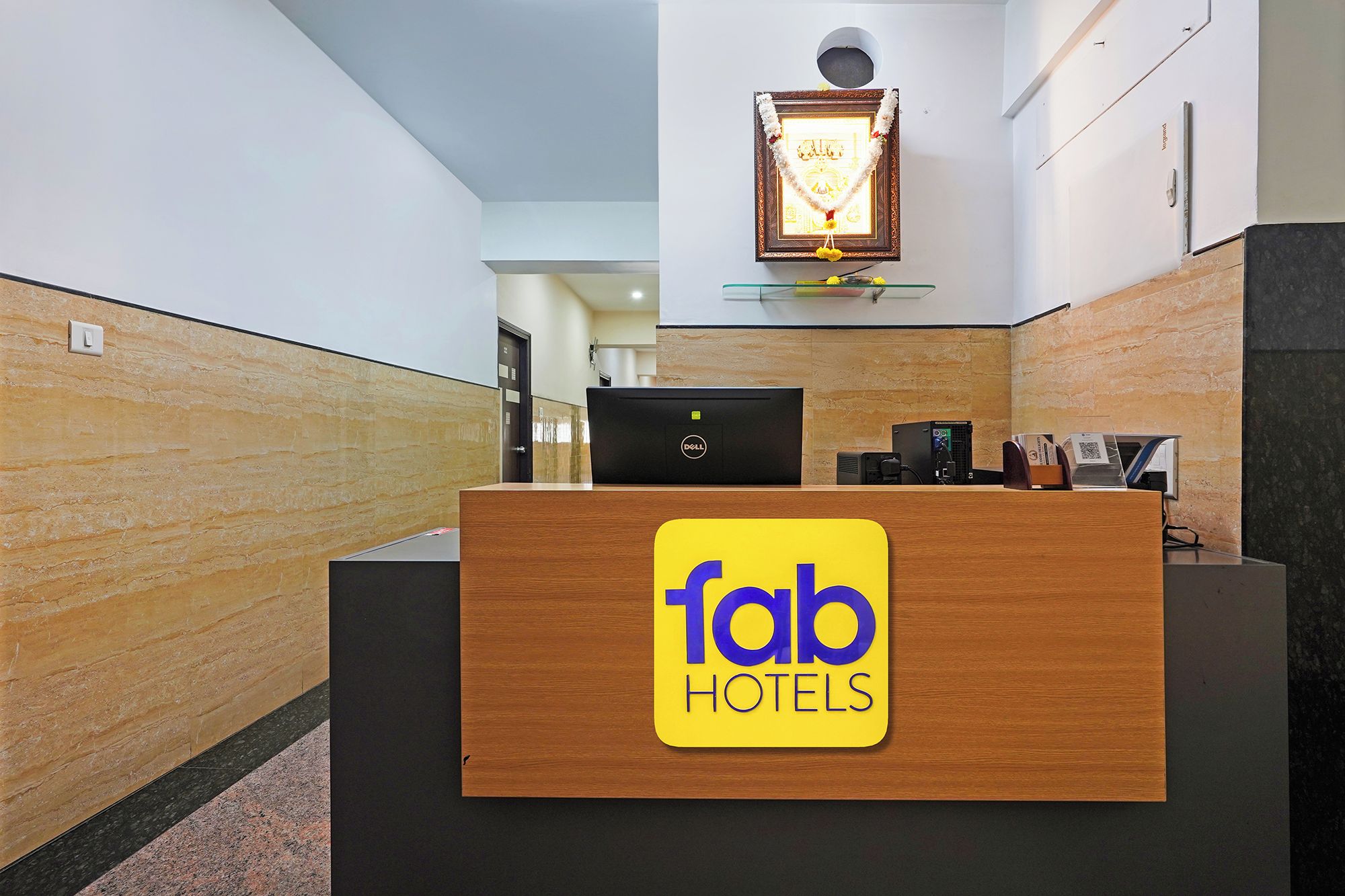 A hotel reception desk with a Dell computer and a framed picture above it.