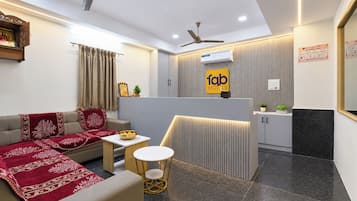 Habitación de hotel moderna con sofá, una mesita redonda y un ventilador de techo.