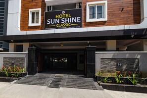 A hotel entrance with a sign reading 'HOTEL SUN SHINE CLASSIC' and 'SERVICE APARTMENT' below.