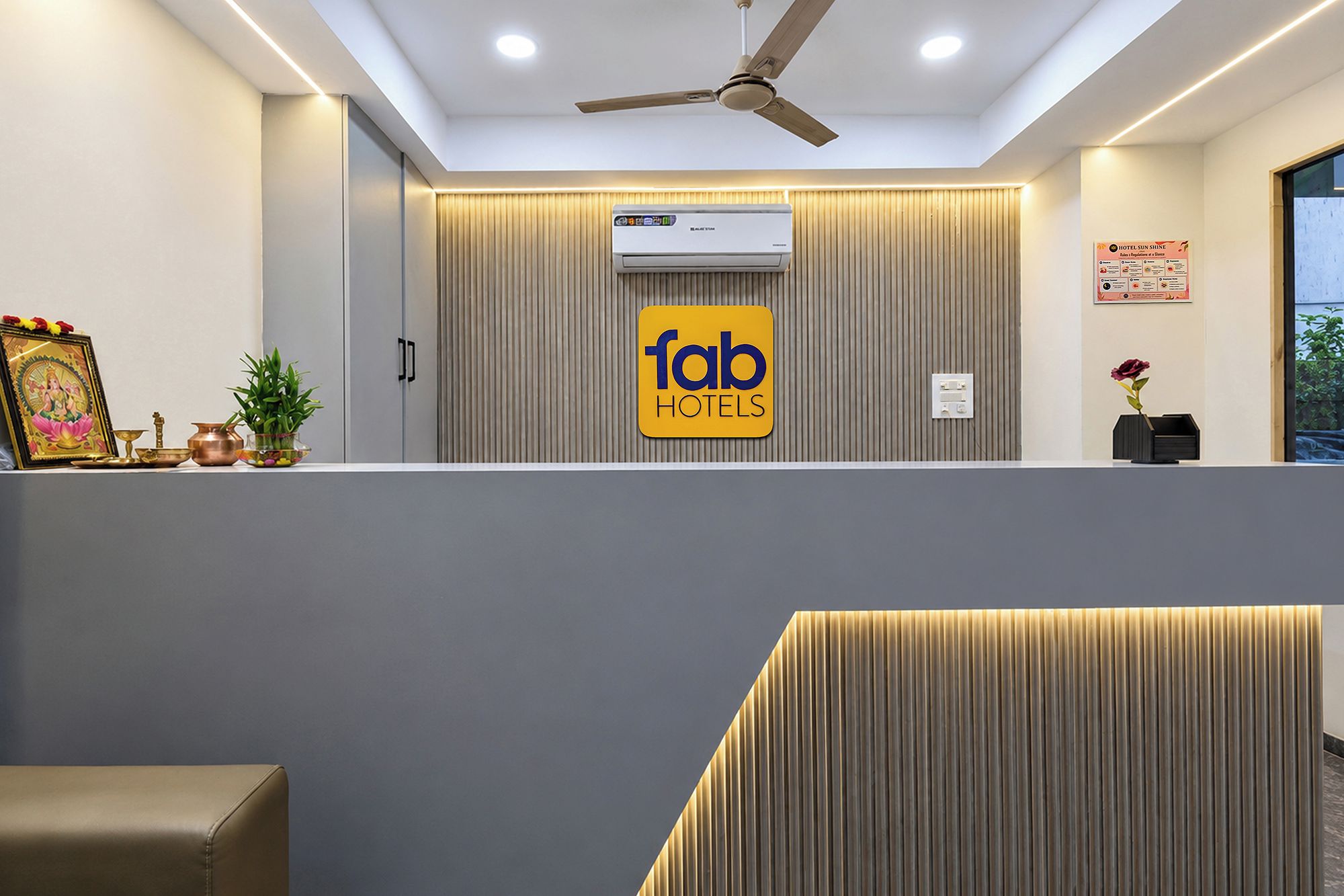 Un área de recepción con ventilador de techo, unidad de aire acondicionado y un cartel que dice 'fab hotels'.