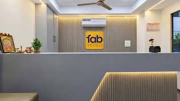 Un área de recepción con ventilador de techo, unidad de aire acondicionado y un cartel que dice 'fab hotels'.