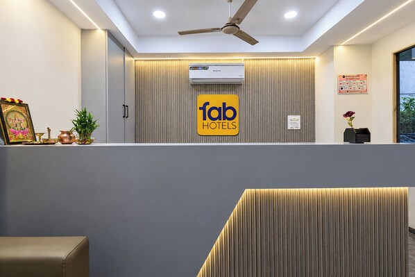A reception area with a ceiling fan, air conditioning unit, and a sign for 'fab hotels'.