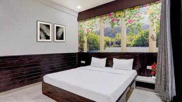 Un dormitorio con una cama grande, un cabecero de madera oscura, una mesita de noche y un mural floral en la pared.