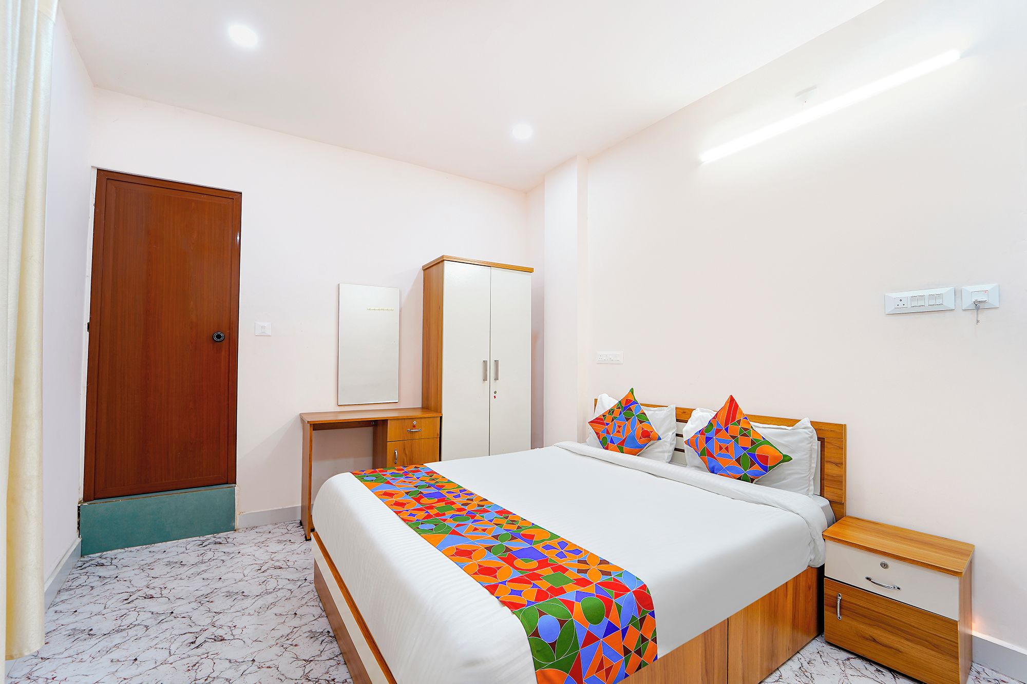 Une chambre d’hôtel avec un lit, des tables de chevet, une armoire et une porte.