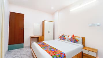 Une chambre d’hôtel avec un lit, des tables de chevet, une armoire et une porte.