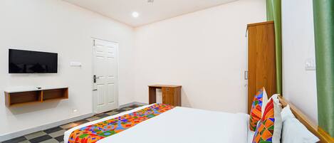 Een slaapkamer met een bed, een televisie, een plafondventilator, een kledingkast en een groen gordijn.