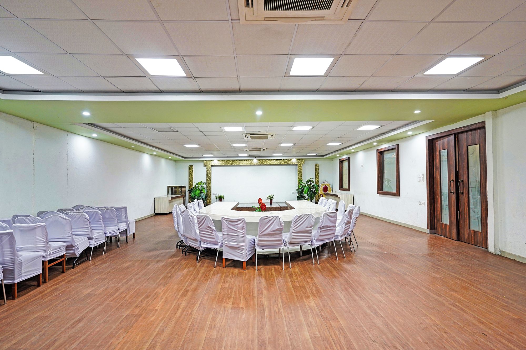 Un salón de conferencias con una mesa redonda, sillas y suelo de madera.