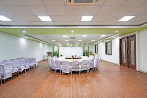 Un salón de conferencias con una mesa redonda, sillas y suelo de madera.
