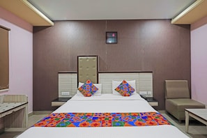 Una habitación de hotel con una cama grande, dos mesitas de noche, una silla y una pequeña mesa.