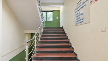 Una escalera con barandillas metálicas que conduce a una puerta verde. Hay un letrero en la pared con texto en un idioma que no es inglés.