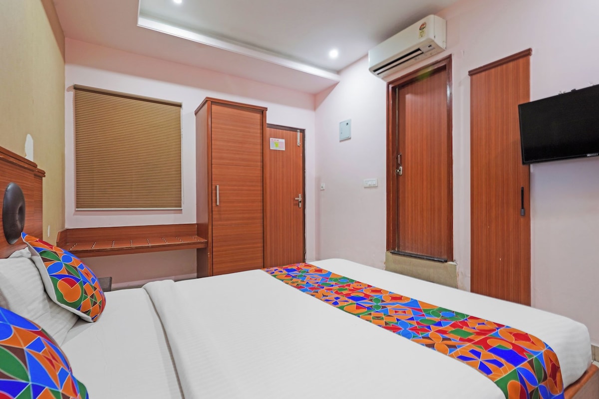 Una habitación de hotel con cama, armario, televisor y aire acondicionado.