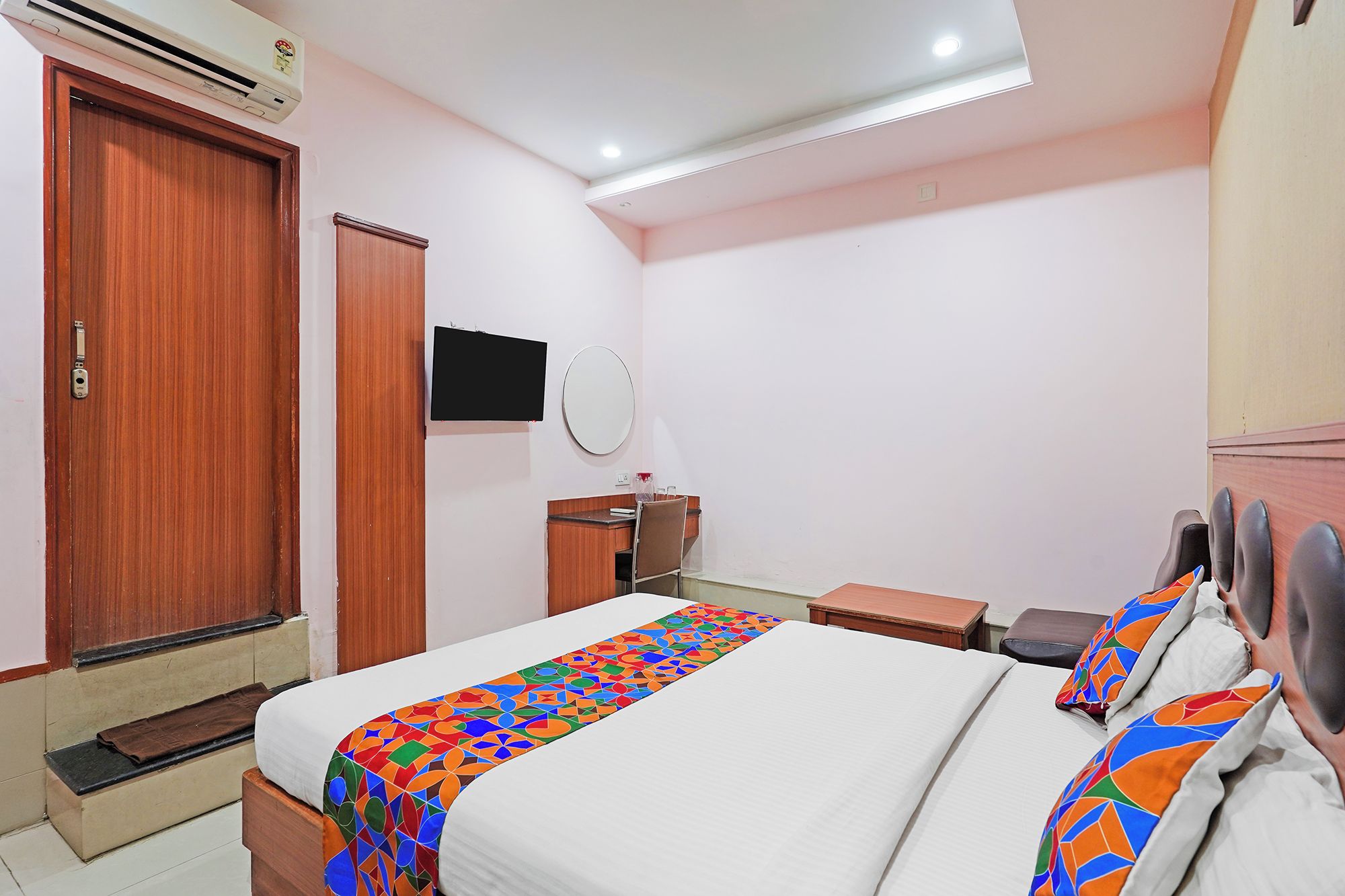 Una habitación de hotel con una cama, un escritorio, una silla, un televisor y un armario.
