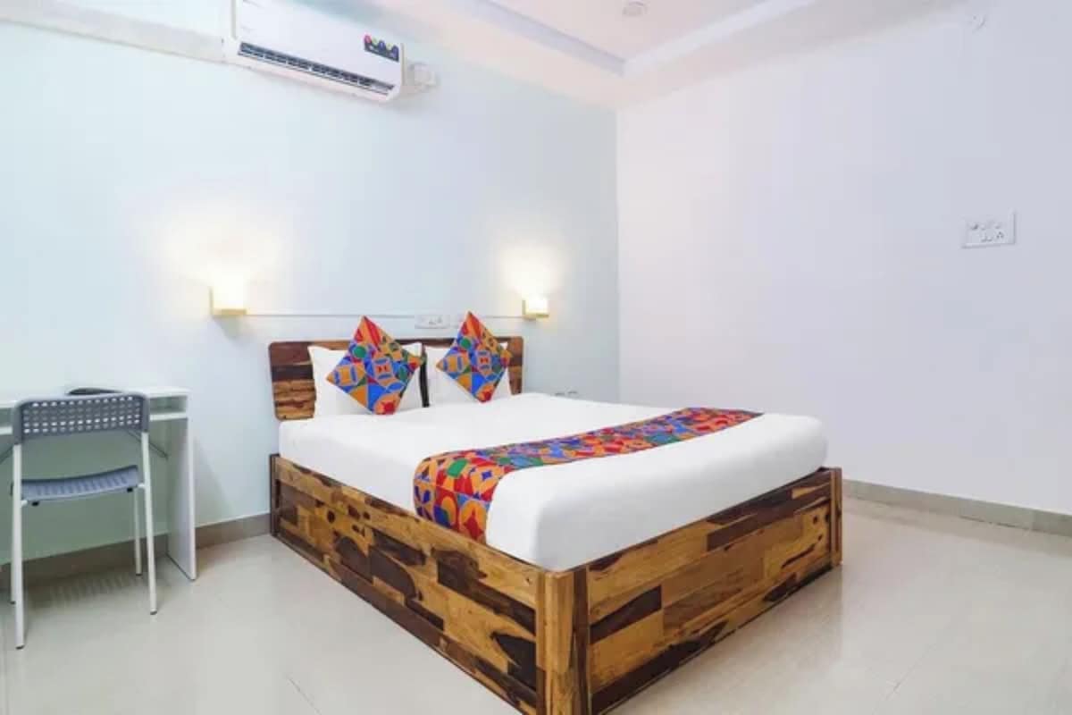 A bedroom with a wooden bed frame, white bedding, and colorful pillows.