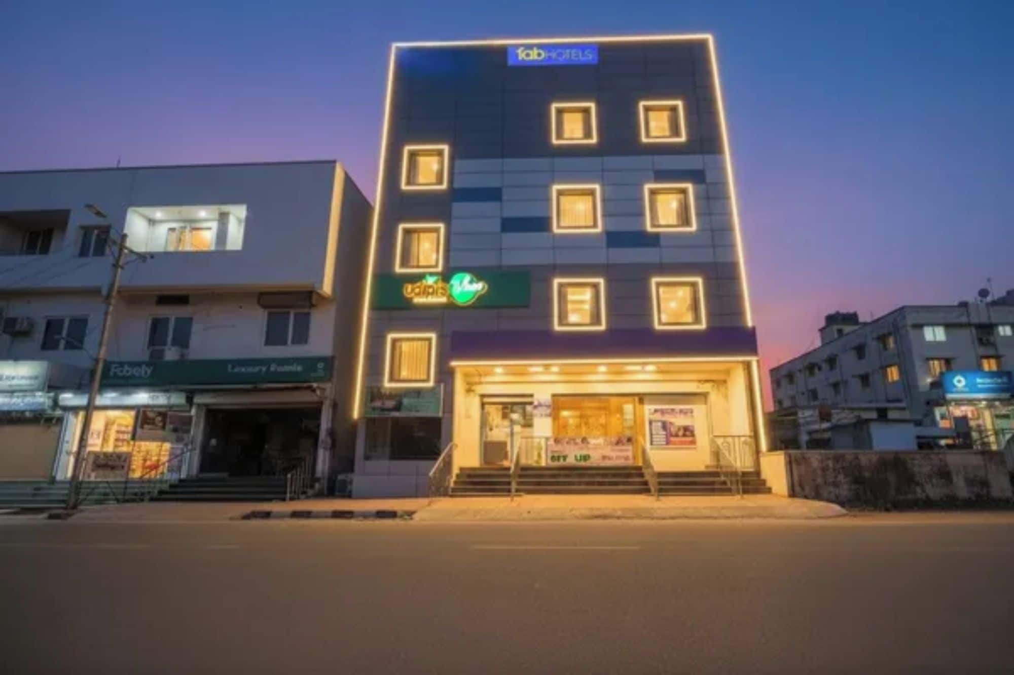 Un hôtel à plusieurs étages doté d’une façade moderne, d’une entrée bien visible avec des marches et d’une enseigne indiquant « Fab Hotels ».